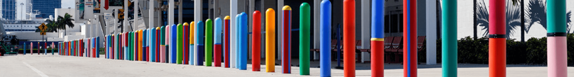 bollards with colorful bollard covers in front of a Port of Miami terminal building